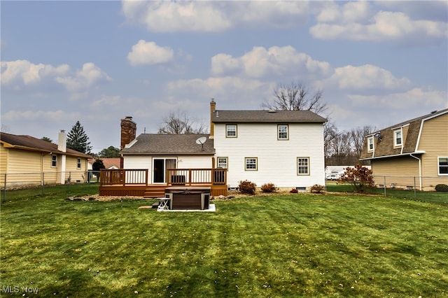 back of property featuring a lawn, a wooden deck, and a hot tub