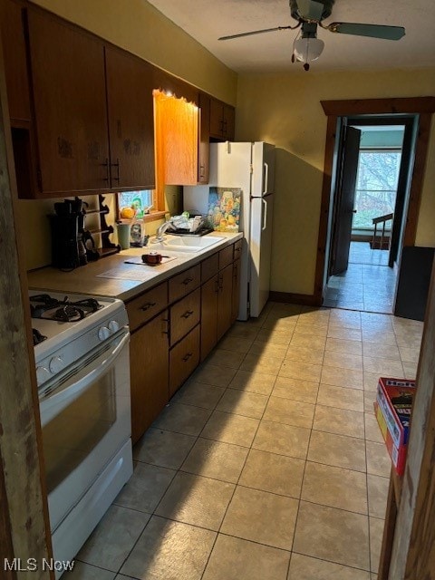 kitchen featuring white gas range oven, ceiling fan, and sink