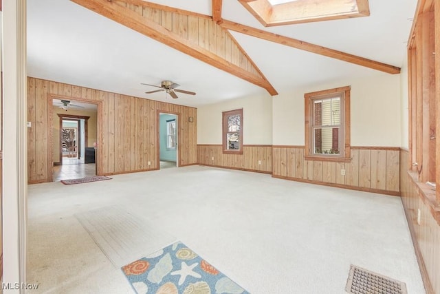 18061 Derr Ave, Beloit, OH 44609 - unfurnished living room with wood walls, carpet flooring, wainscoting, a skylight, and ceiling fan