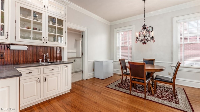 dining area featuring light hardwood / wood-style floors, a notable chandelier, crown molding, and sink