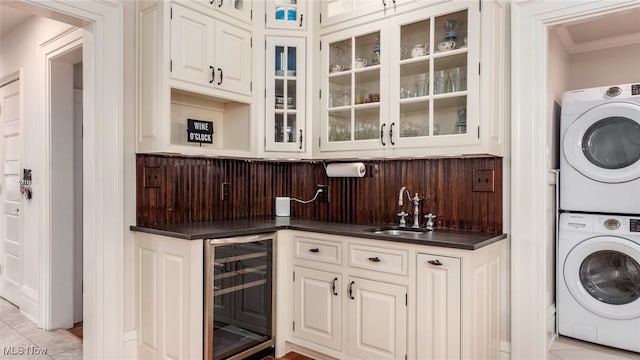 interior space featuring crown molding, sink, light tile patterned floors, stacked washer and clothes dryer, and wine cooler