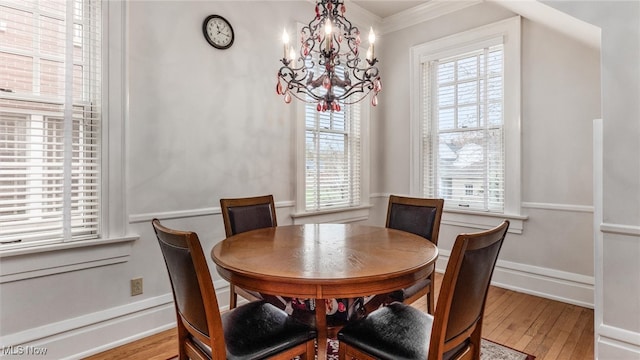 dining area with a chandelier, light hardwood / wood-style floors, a wealth of natural light, and ornamental molding