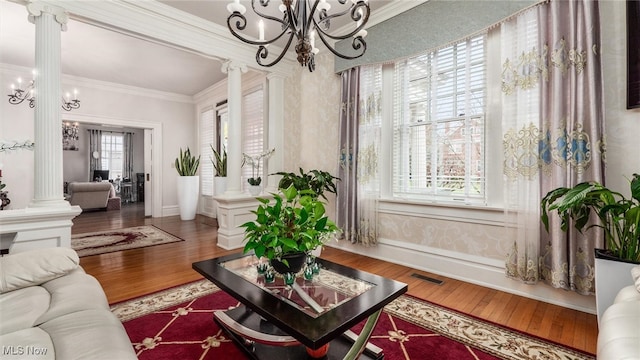 living room with wood-type flooring, ornate columns, and crown molding