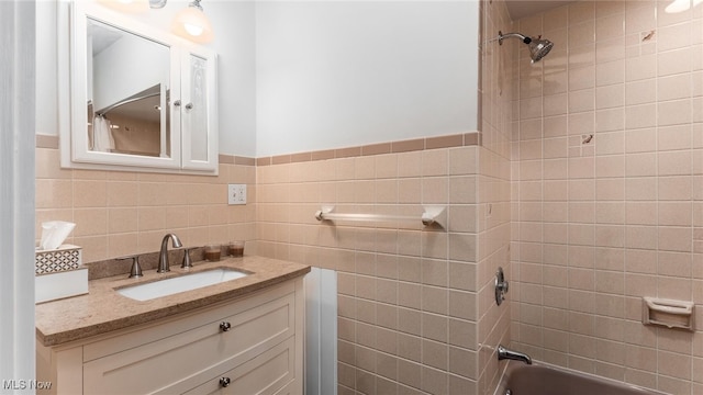 bathroom with vanity, tile walls, and tiled shower / bath