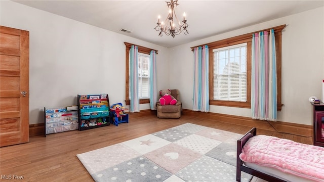 bedroom featuring light hardwood / wood-style floors, an inviting chandelier, and multiple windows