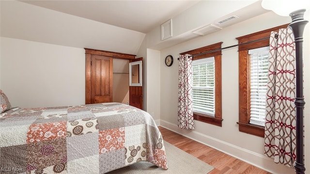 bedroom with light wood-type flooring and vaulted ceiling