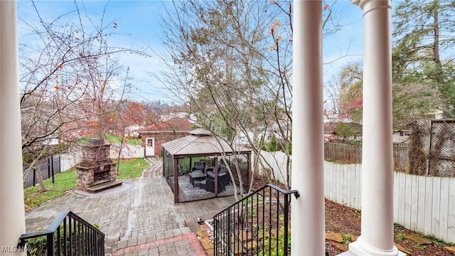 view of patio featuring a gazebo and an outdoor stone fireplace