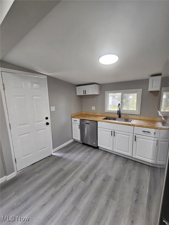 kitchen featuring butcher block countertops, white cabinetry, sink, and stainless steel dishwasher