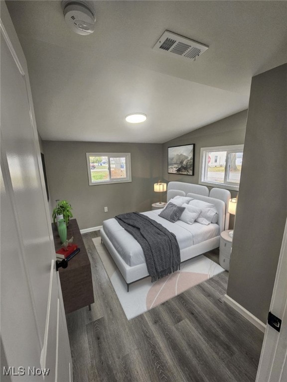 bedroom with dark hardwood / wood-style flooring, multiple windows, and lofted ceiling