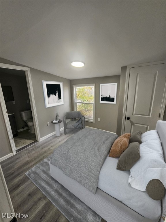 bedroom featuring ensuite bathroom, vaulted ceiling, and dark wood-type flooring