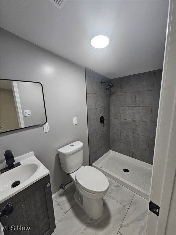 bathroom with vanity, toilet, and a tile shower