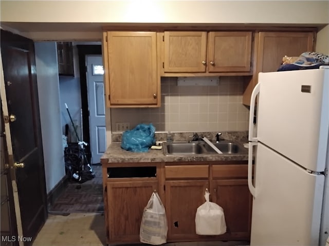 kitchen featuring white refrigerator, backsplash, and sink