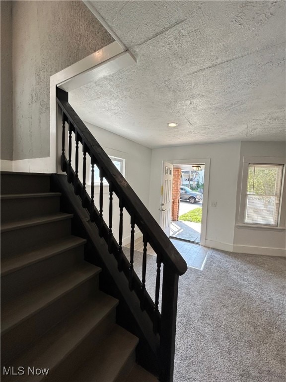 stairway featuring carpet floors and a textured ceiling