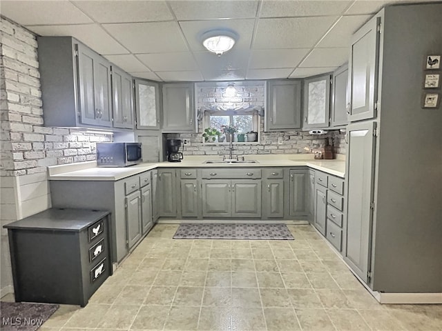 kitchen featuring a paneled ceiling, gray cabinetry, and sink