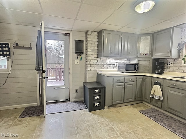 kitchen with a paneled ceiling, gray cabinetry, and light tile patterned floors