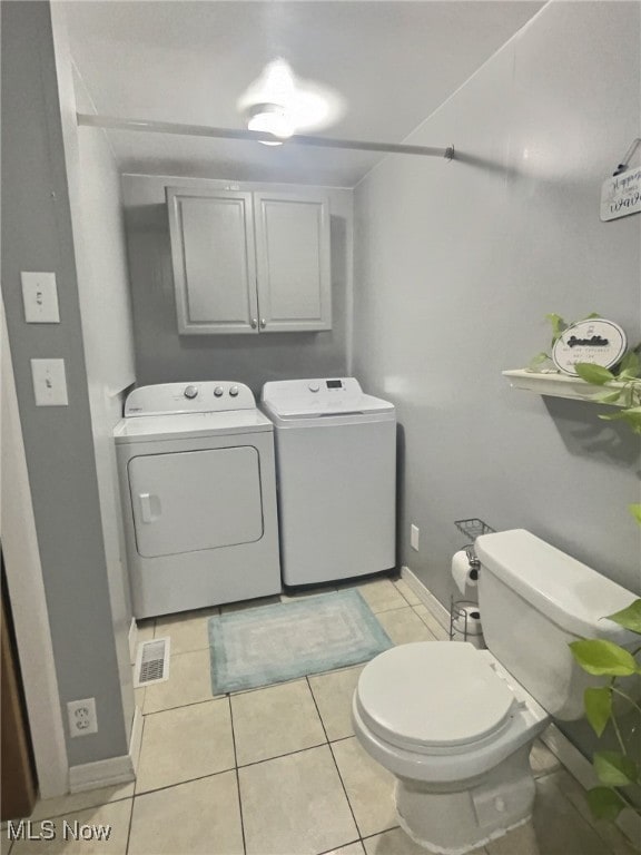 bathroom featuring washing machine and clothes dryer, tile patterned floors, and toilet