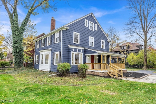 rear view of property featuring a yard and covered porch