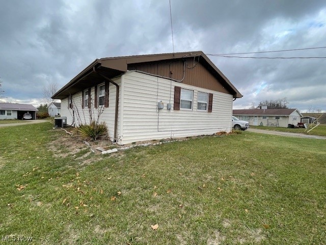 view of side of home with a lawn and central air condition unit