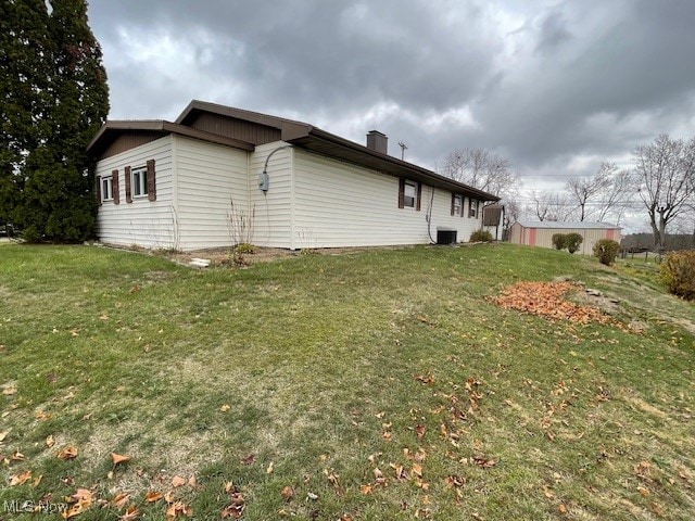 view of side of property with central air condition unit and a lawn