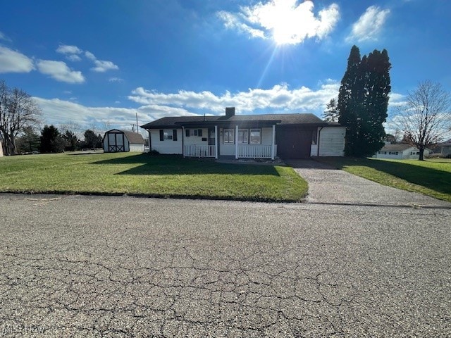 view of front of property with a front yard, a porch, and a storage unit