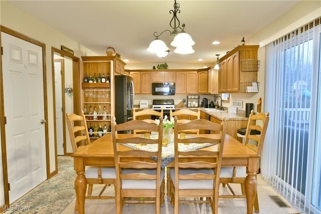 dining space with sink, light tile patterned floors, and a notable chandelier