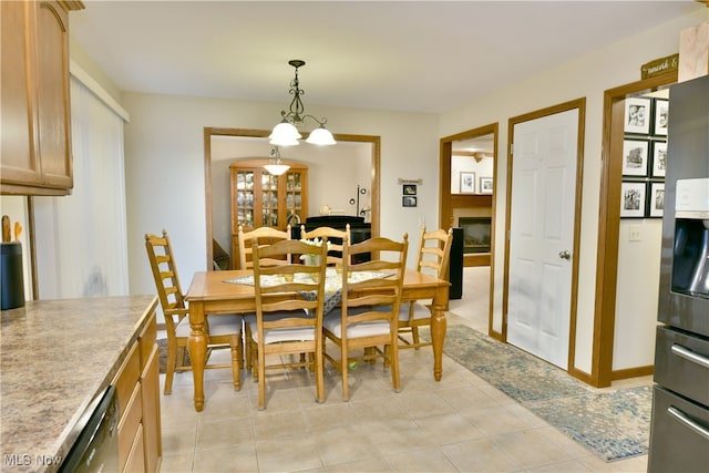 tiled dining area with a fireplace and a chandelier