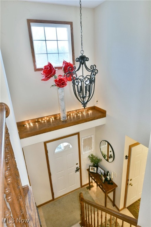 carpeted foyer entrance with a chandelier