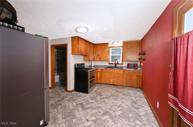 kitchen with sink, a textured ceiling, and appliances with stainless steel finishes