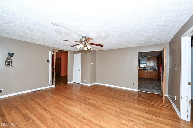 unfurnished room with ceiling fan, light wood-type flooring, and a textured ceiling