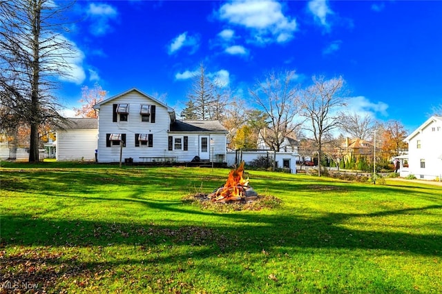 rear view of house with a fire pit and a yard