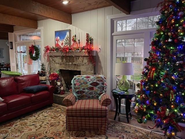 living room with beam ceiling, wood walls, a fireplace, and wood ceiling