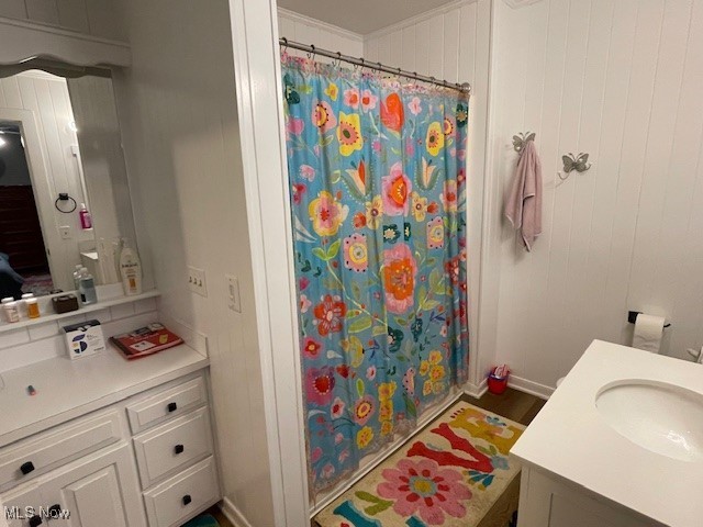 bathroom featuring vanity, walk in shower, crown molding, and wood walls