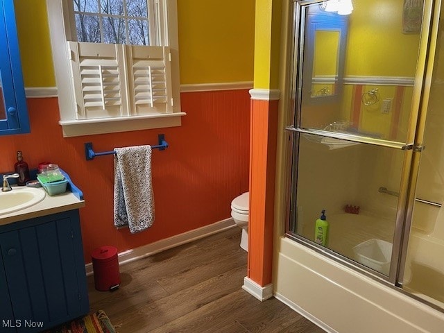 full bathroom featuring toilet, vanity, enclosed tub / shower combo, and hardwood / wood-style flooring