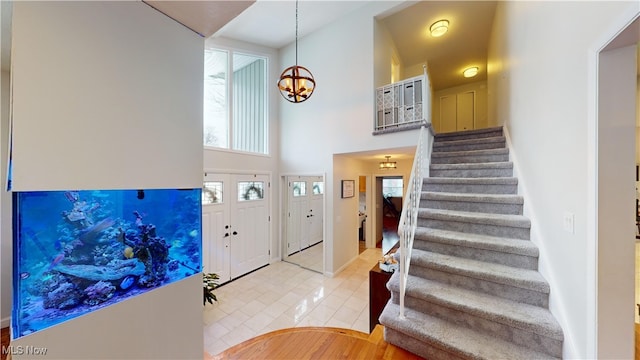 entryway with a high ceiling, light hardwood / wood-style floors, and an inviting chandelier