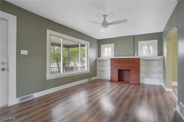 unfurnished living room featuring hardwood / wood-style flooring, a brick fireplace, and ceiling fan