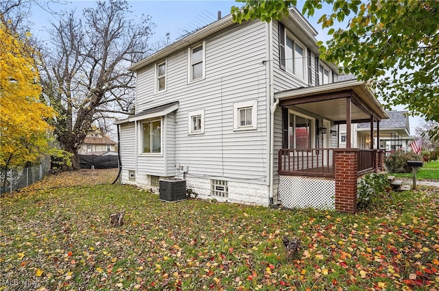 view of side of home with central AC unit, covered porch, and a lawn