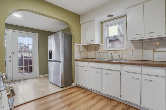 kitchen featuring stainless steel fridge, light wood-type flooring, and white cabinetry