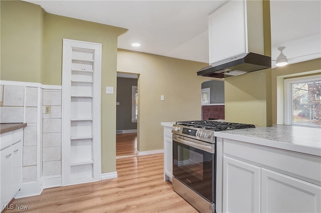 kitchen featuring white cabinets, light wood-type flooring, exhaust hood, and gas range