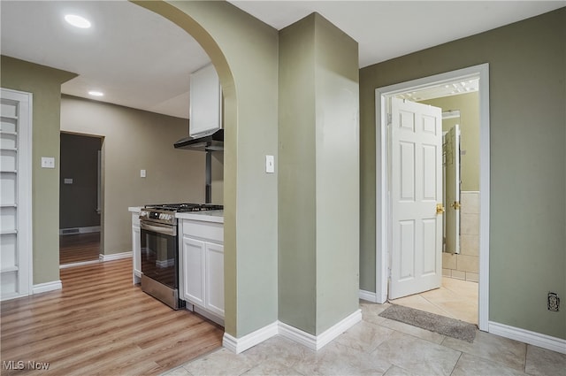 kitchen with light hardwood / wood-style floors, stainless steel gas range oven, white cabinetry, and range hood