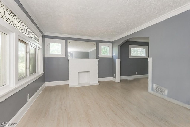 unfurnished living room featuring light hardwood / wood-style floors, a wealth of natural light, and crown molding