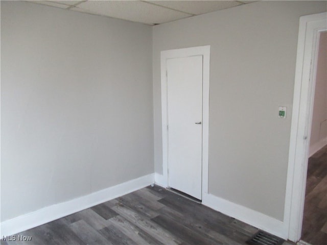 spare room featuring a paneled ceiling and dark wood-type flooring