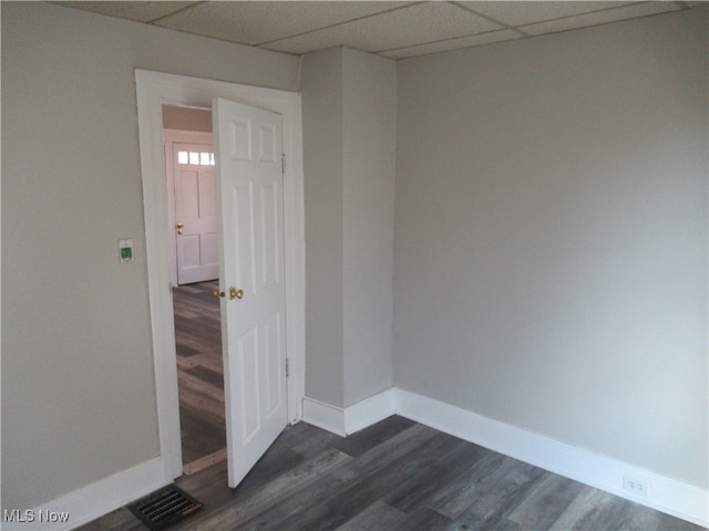 spare room featuring a paneled ceiling and dark hardwood / wood-style floors