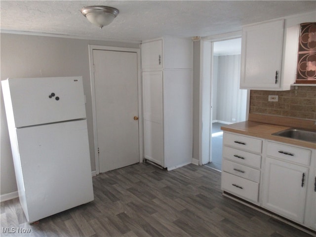 kitchen featuring white cabinetry, sink, dark hardwood / wood-style flooring, white fridge, and decorative backsplash