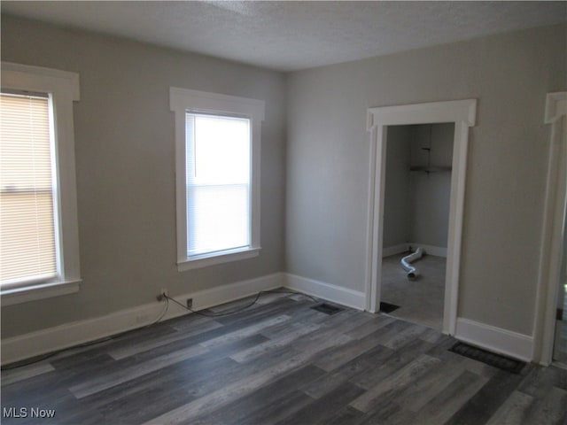 unfurnished bedroom with a textured ceiling, a closet, and dark wood-type flooring