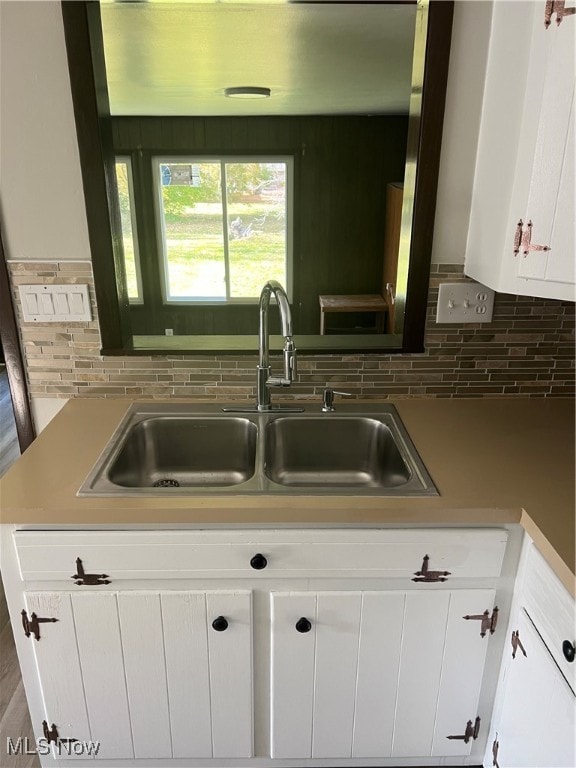 kitchen with backsplash, sink, and white cabinets