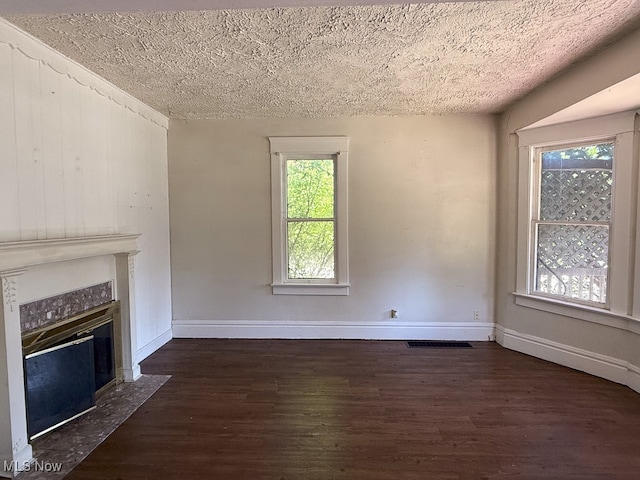 unfurnished living room featuring plenty of natural light, dark wood-type flooring, and a textured ceiling