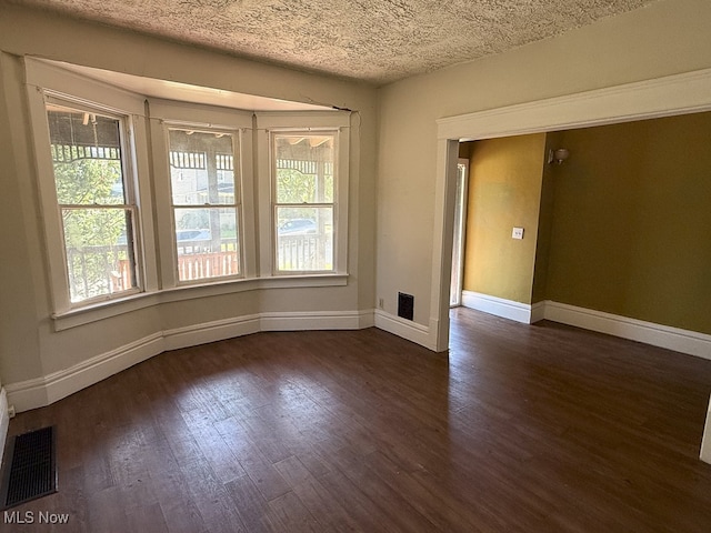 unfurnished room featuring a textured ceiling and dark hardwood / wood-style flooring