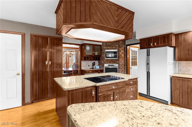 kitchen featuring tasteful backsplash, custom range hood, black appliances, light hardwood / wood-style flooring, and a kitchen island