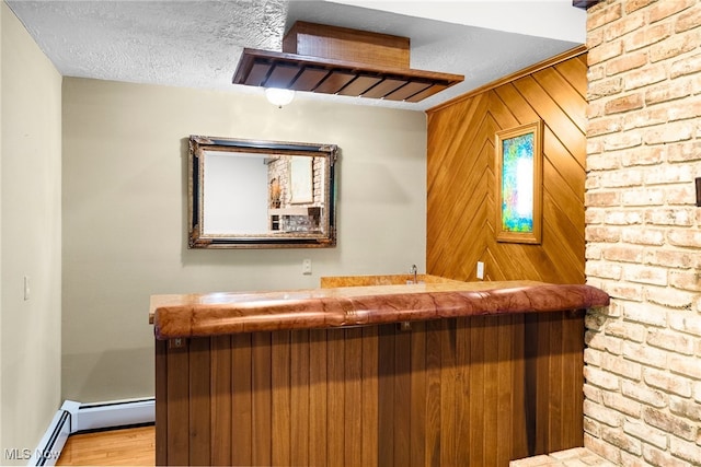 bar with light hardwood / wood-style floors, baseboard heating, a textured ceiling, and wooden walls