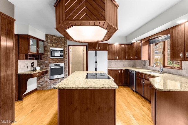 kitchen featuring light stone counters, sink, black appliances, a center island, and light hardwood / wood-style floors